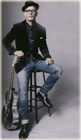 Man in studio sitting on stool with guitar